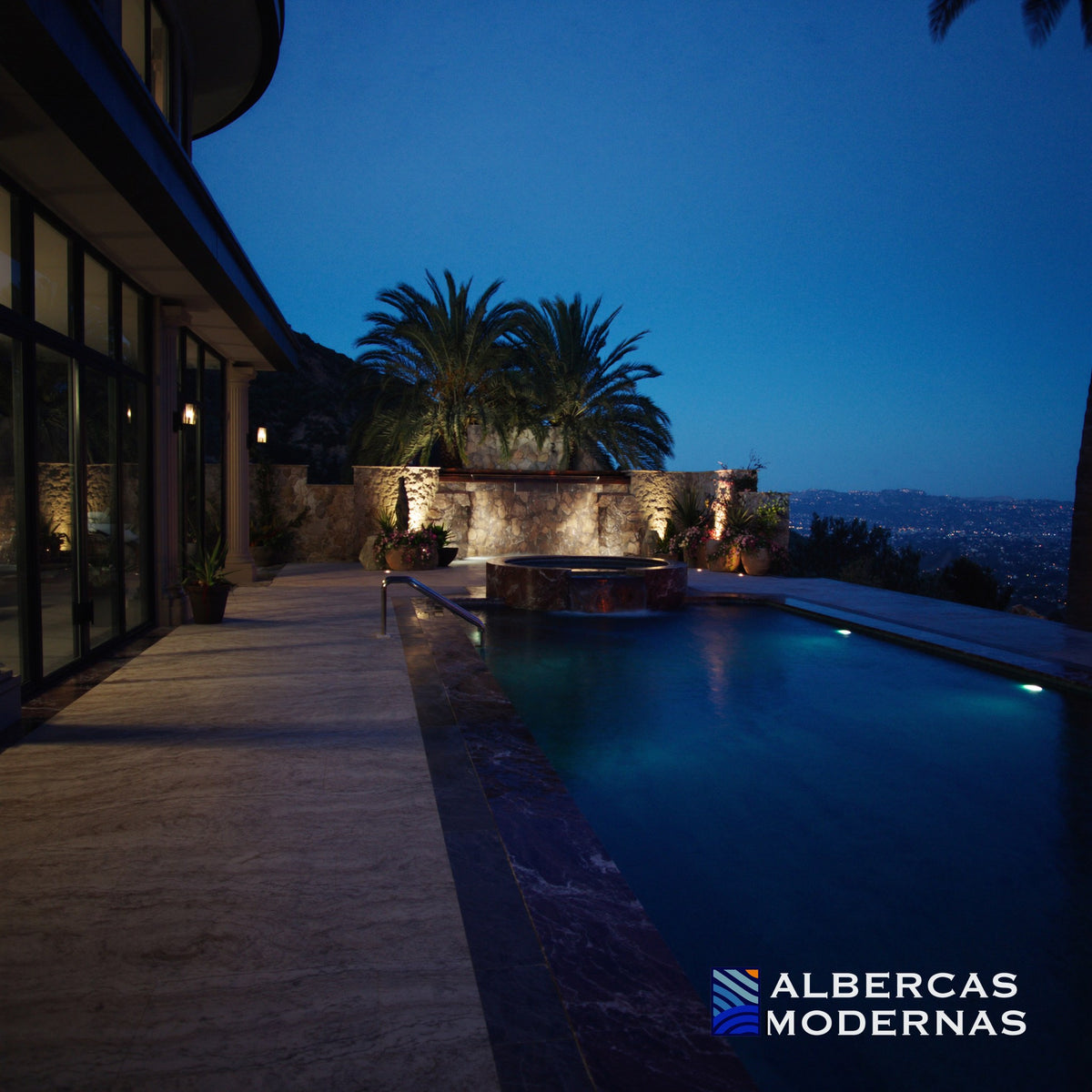 Alberca Moderna Signature con jacuzzi integrado y muro de piedra al anochecer — imagen ilustrativa